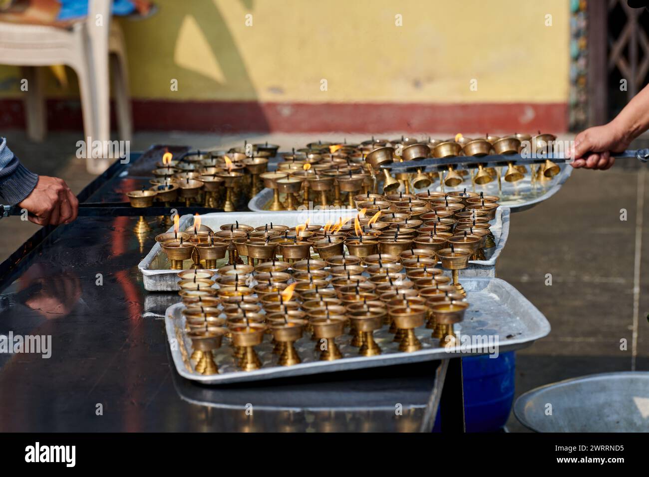 Nepali temple staff pour out candle oil after wick burns out for