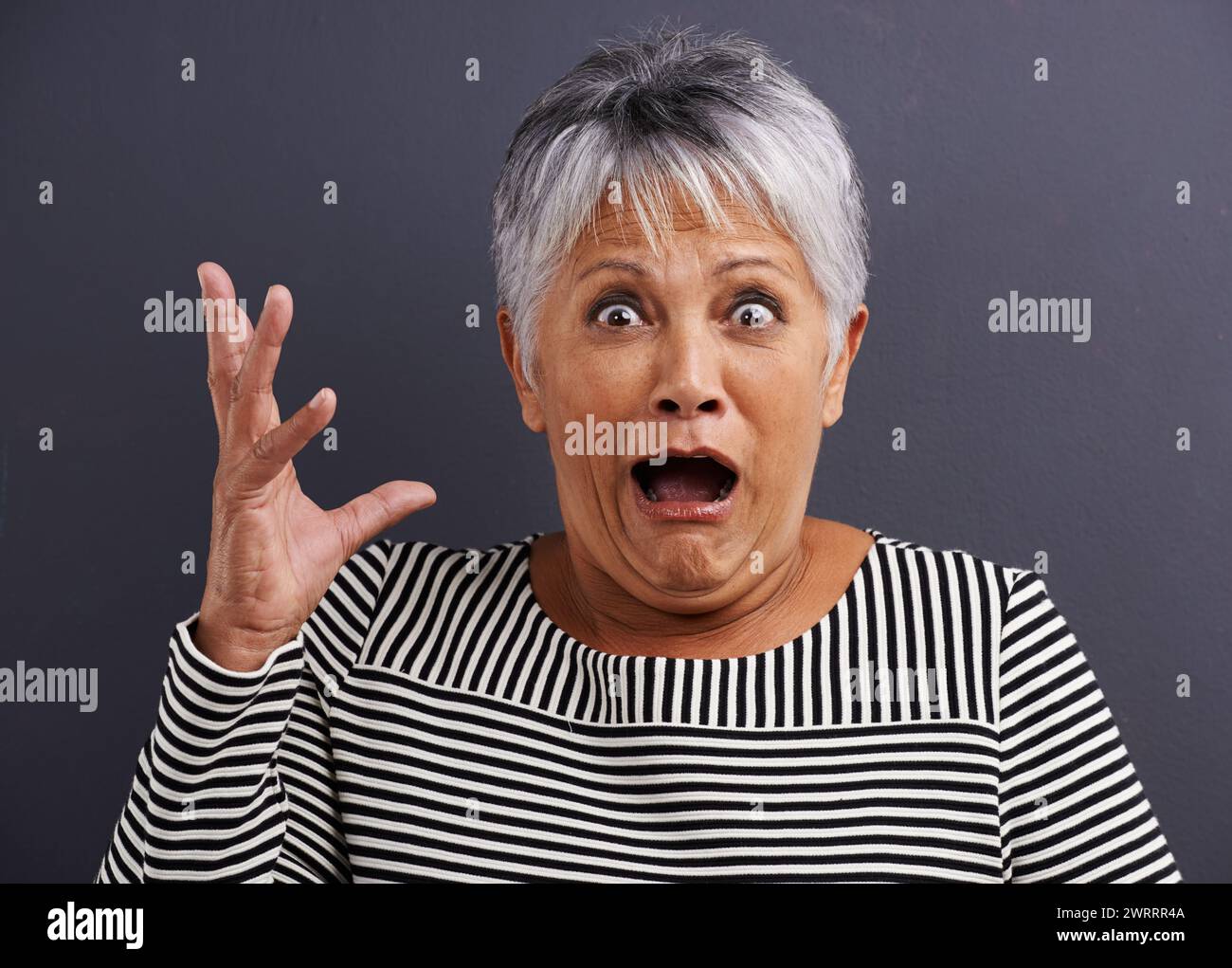 Shock, portrait and senior woman in studio with fear, scared and terror facial expression. Surprise, crazy and elderly female person with terrified or Stock Photo