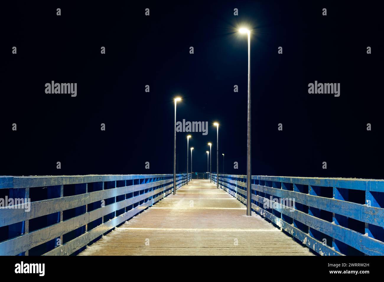 Lampposts along pier going into night darkness above sea symbolize