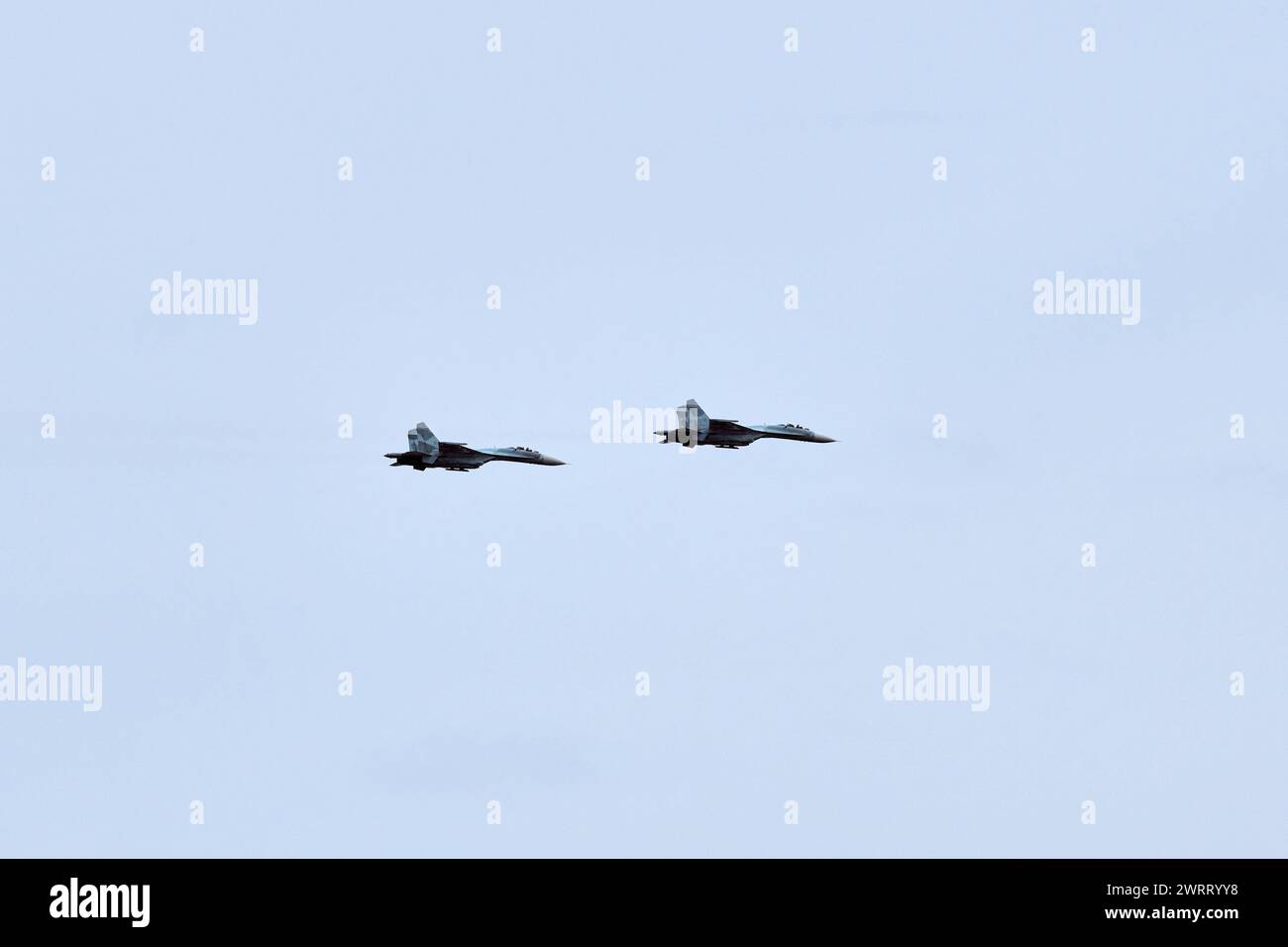 Two Russian military fighter planes armed with missiles flies in blue ...