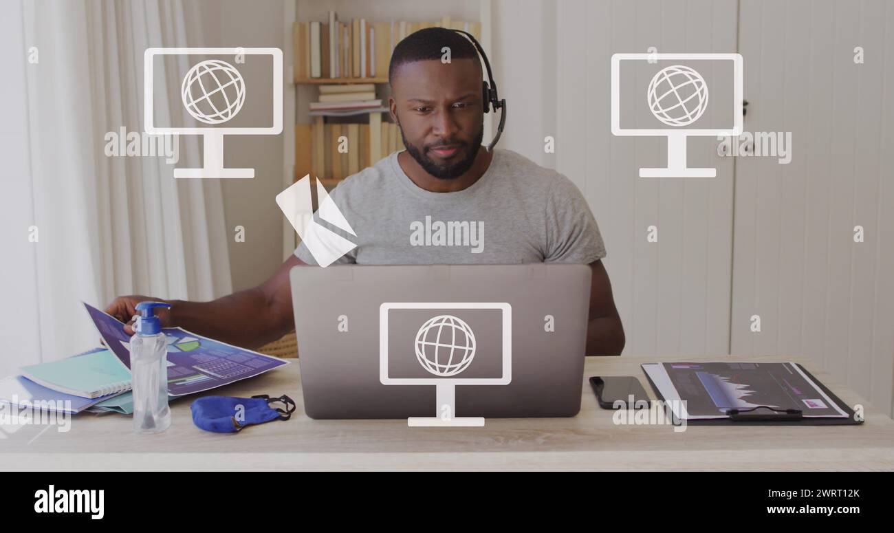 Image of screens with globes icons over african american man using laptop Stock Photo