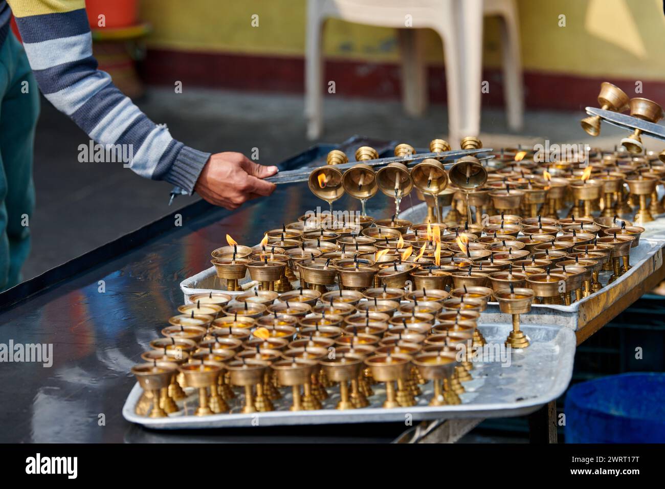 Nepali temple staff pour out candle oil after wick burns out for