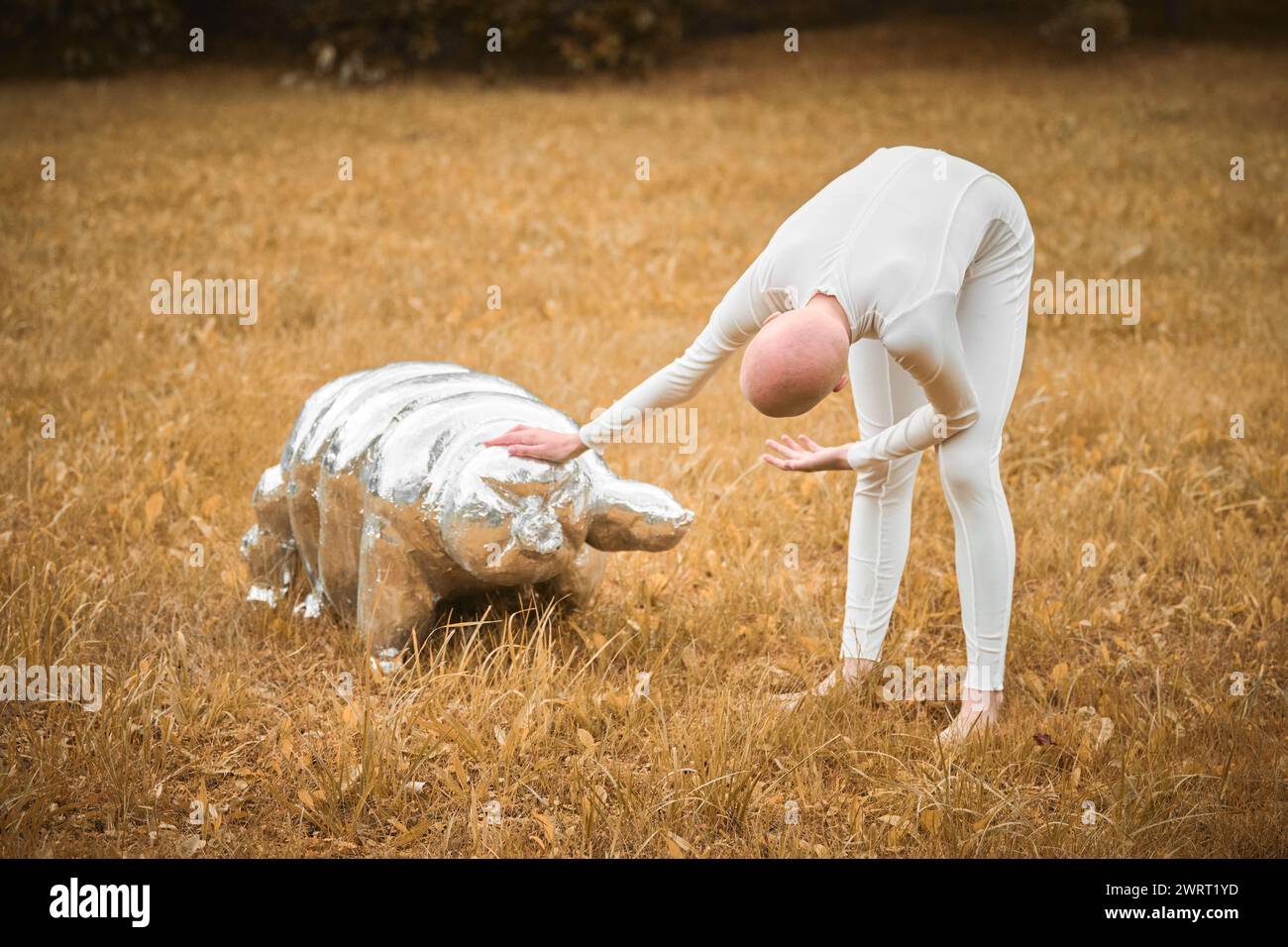 Portrait of young hairless girl with alopecia in white cloth playing with tardigrade toy in fall park, surreal scene with bald teenage girl reflect on Stock Photo