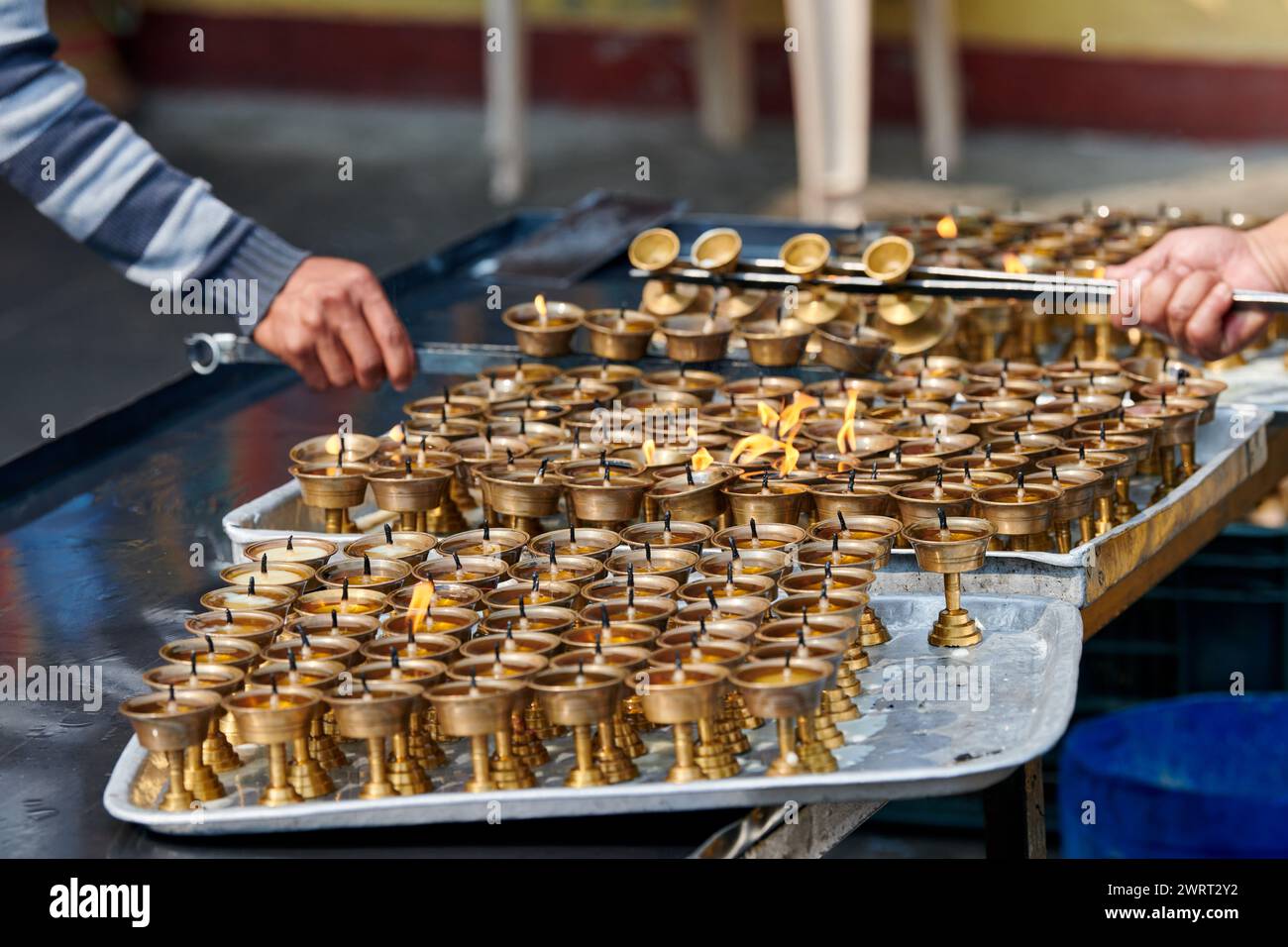 Nepali temple staff pour out candle oil after wick burns out for