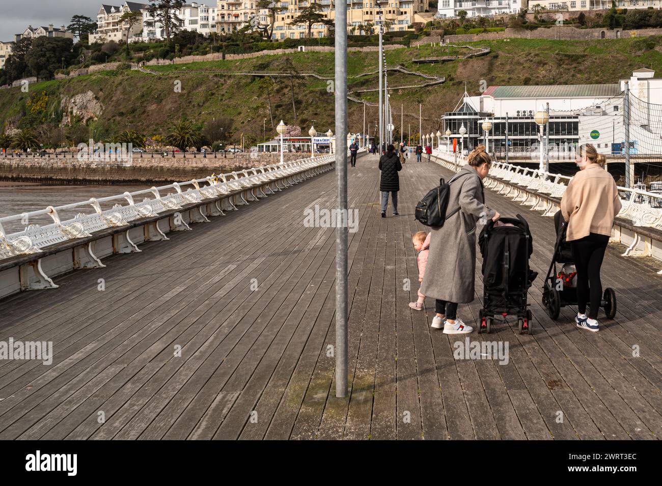 Torquay Pier with the Rock Walk in the background. Two young mothers ...