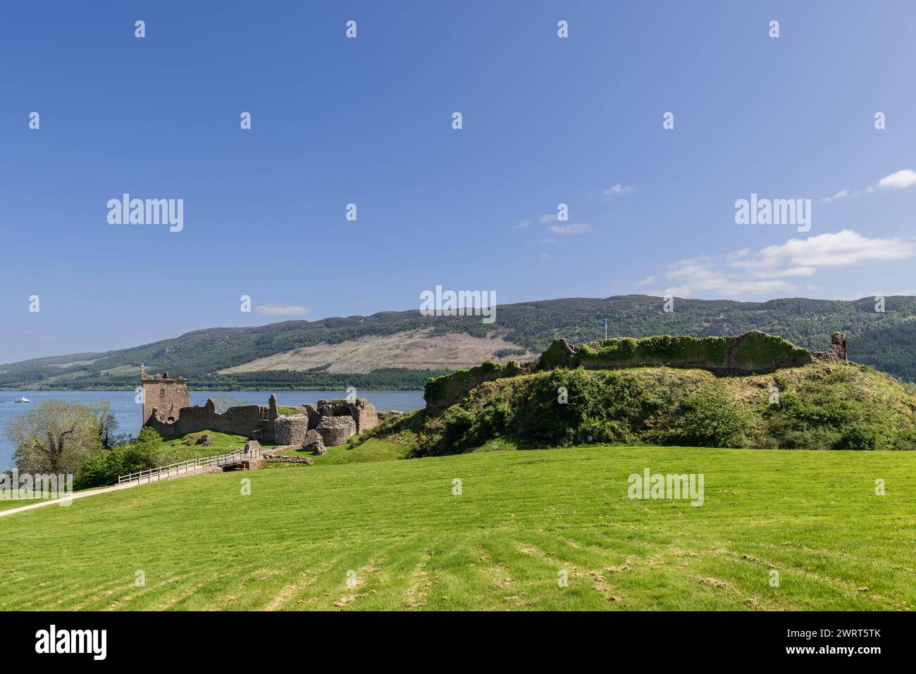 A vibrant view captures Urquhart Castle ancient ruins against the backdrop of Loch Ness and the verdant Scottish Highlands Stock Photo