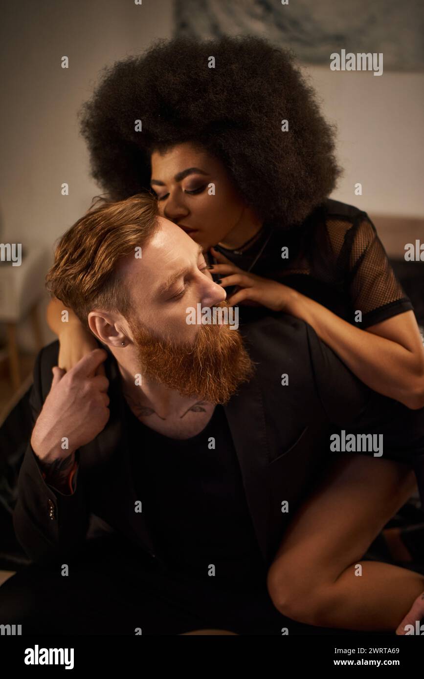 passionate night of multicultural couple at home, curly african american woman kissing tattooed man Stock Photo