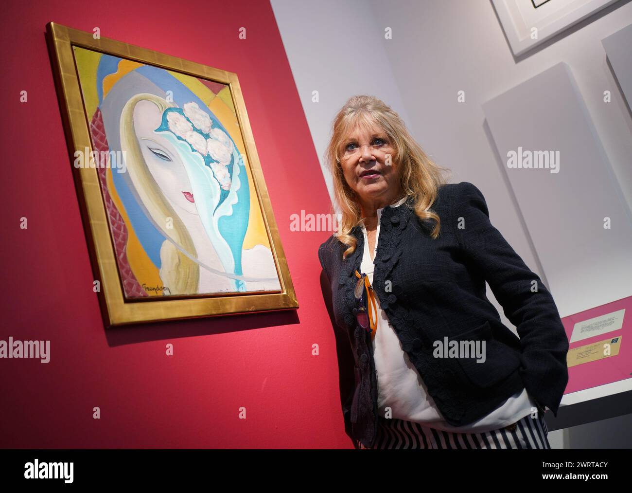 Pattie Boyd posing next to original cover art for the 1970 Derek and the Dominos album Layla and Other Assorted Love Songs, circa 1950-55, by artist Emile Théodore Frandsen de Schomberg, estimate £40,000-60,000, during a press call at Christie's in London, to publicise the forthcoming 'The Pattie Boyd Collection sale' at the auction house. Picture date: Thursday March 14, 2024. Stock Photo