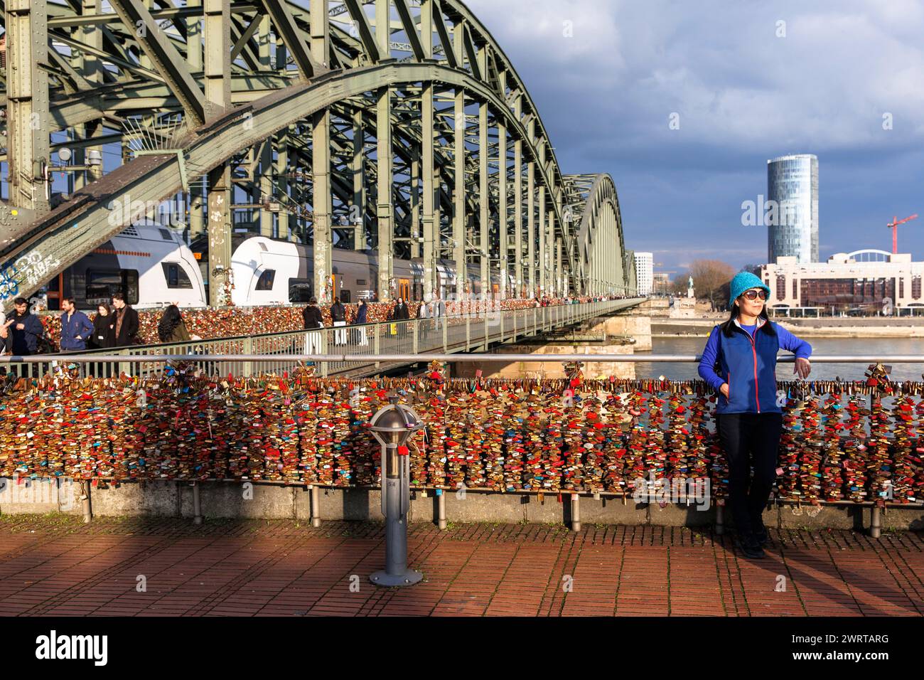 love locks at Hohenzollern Bridge, view over the Rhine to the KoelnTriangle skyscraper and the Hyatt Hotel in the Deutz district, tourist has her phot Stock Photo