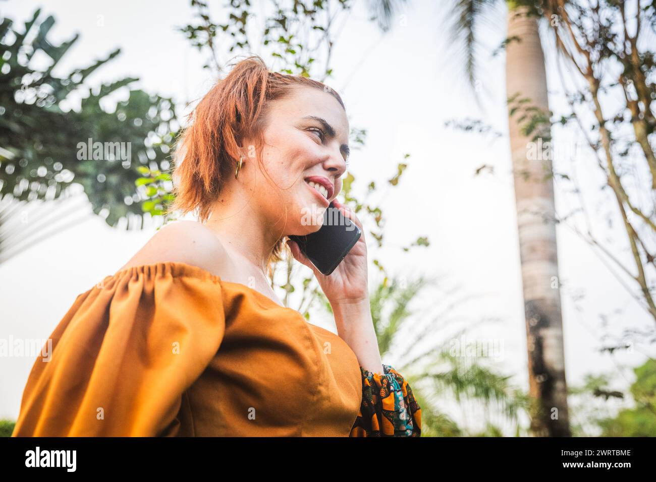 A woman makes a phone call while in a botanical garden. Stock Photo