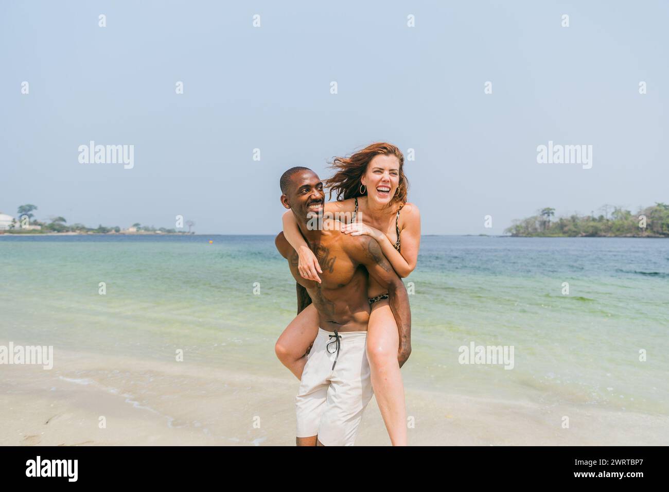 A couple of lovers have fun on the beach, interracial couple on vacation. Stock Photo