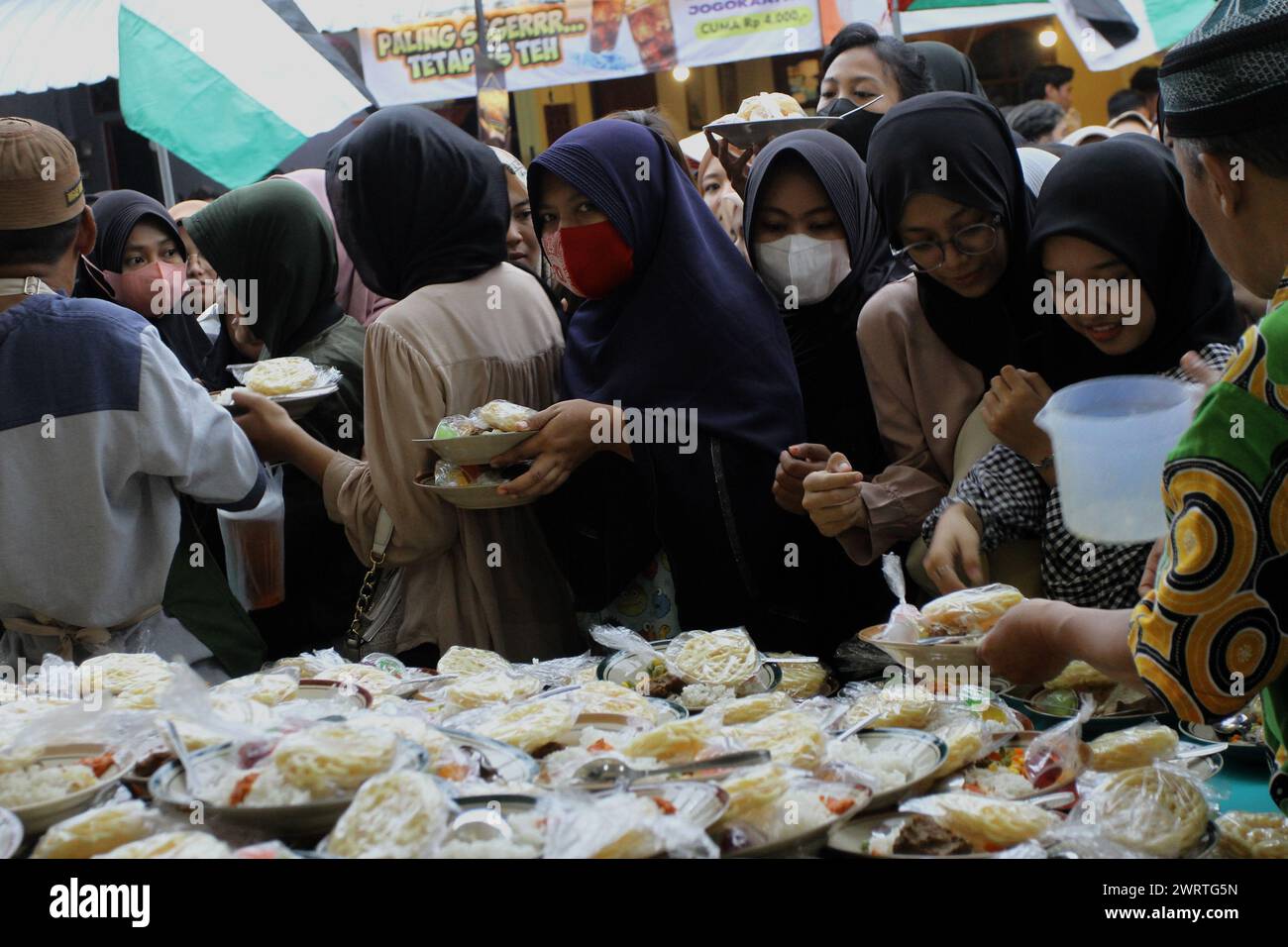 March 14, 2024, Yogyakarta, Special Region Of Yogyakarta, Indonesia: People queue to get meals for breaking fast during the Holy Month of Ramadan locally known as ''Takjil'' at the Jogokariyan Mosque. During Ramadan, the mosque prepares 3,5000 portions of takjil which are distributed free of charge to people. (Credit Image: © Angga Budhiyanto/ZUMA Press Wire) EDITORIAL USAGE ONLY! Not for Commercial USAGE! Stock Photo