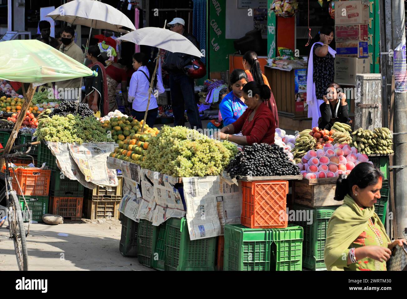 Market stall with fresh fruit and vegetables and people shopping