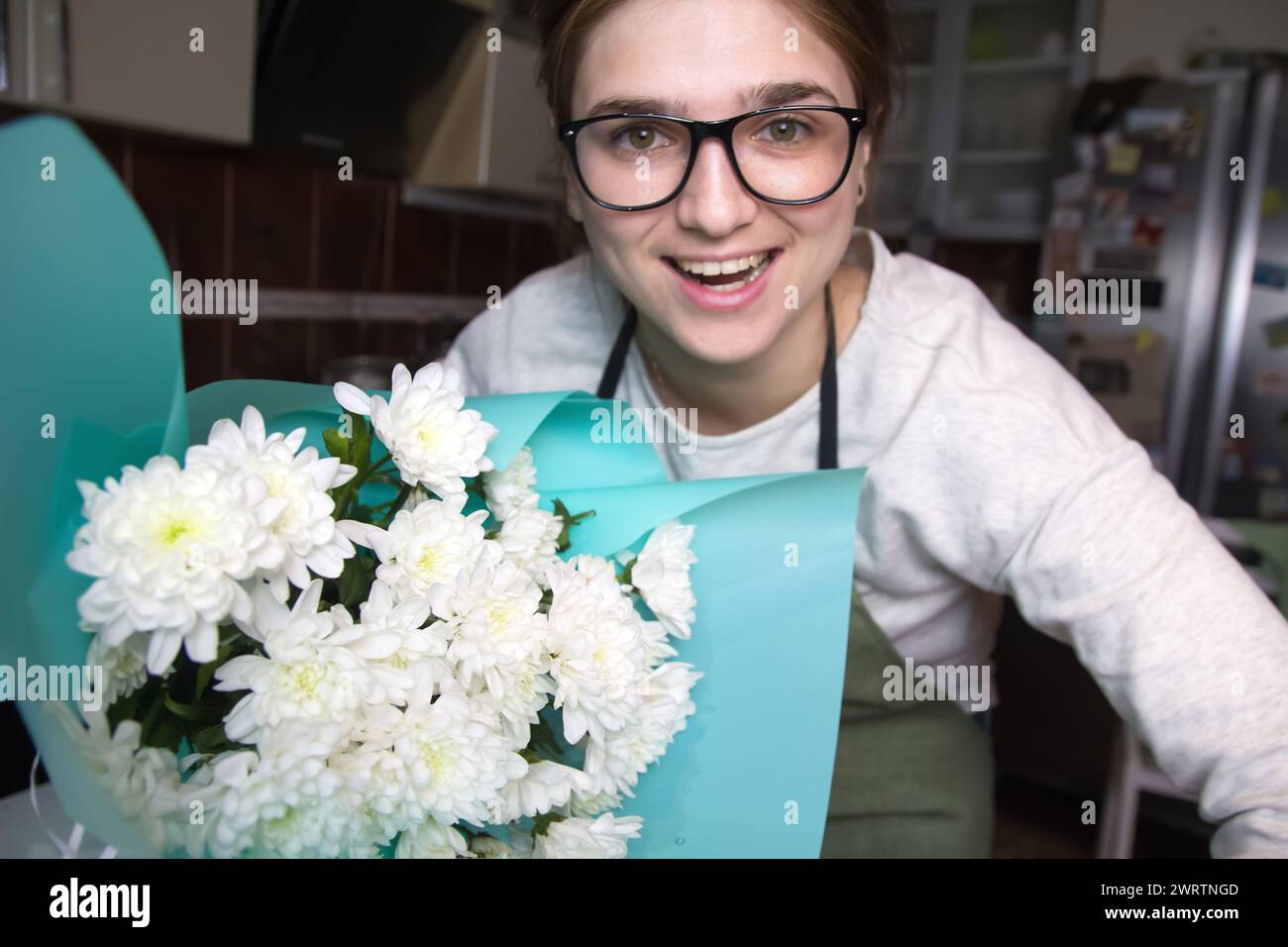 Florist woman smiling holding bouquet with white daisies. This scene captures the artistry of a small business florist in action. Out of focus. Stock Photo