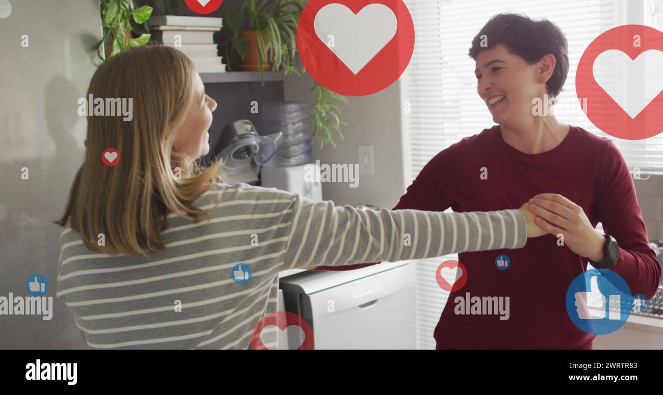 Image of hearts and like icons over caucasian female couple dancing Stock Photo