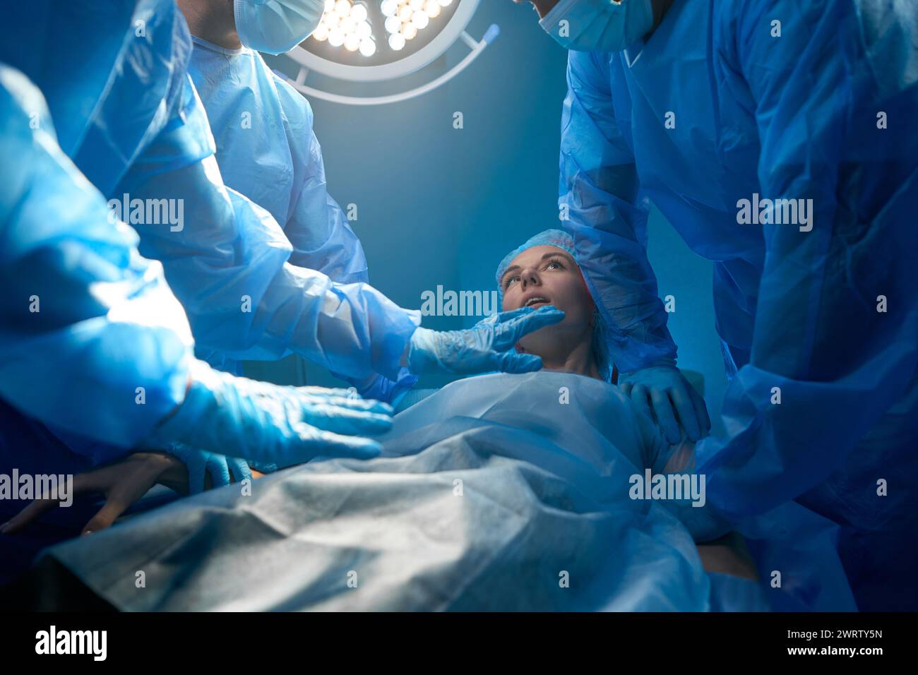Woman patient waking up after surgery surrounded with professional