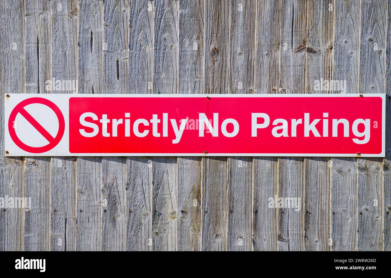 A Strictly No Parking sign fixed to a slatted wooden fence Stock Photo