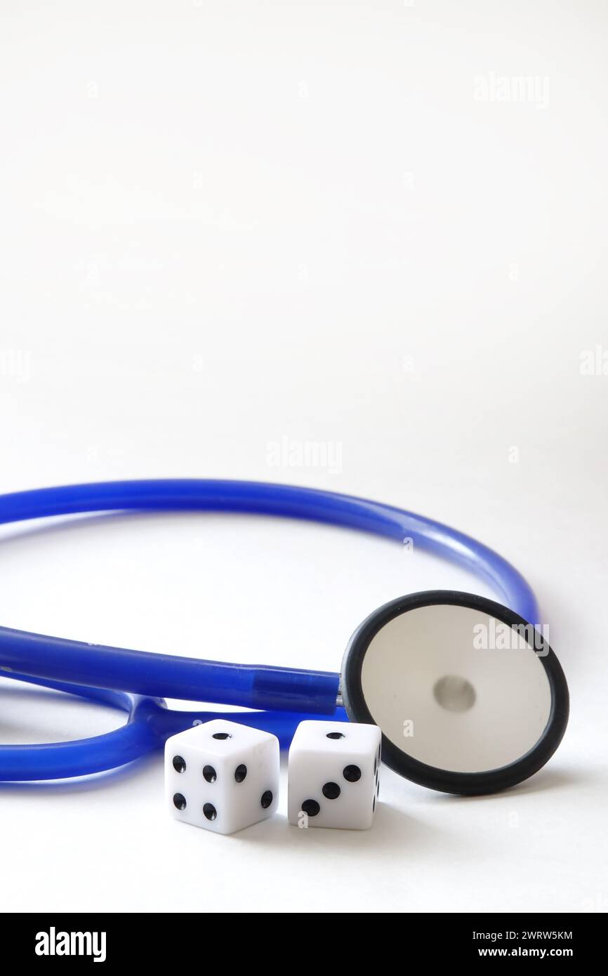 Blue stethoscope beside two dice on white background Stock Photo