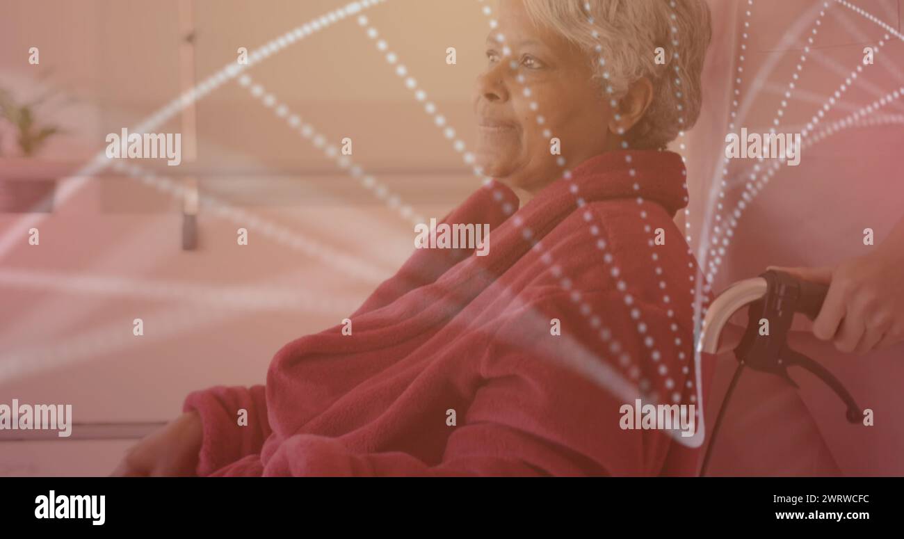 Image of dna strand over diverse nurse and senior biracial female patient in wheelchair Stock Photo