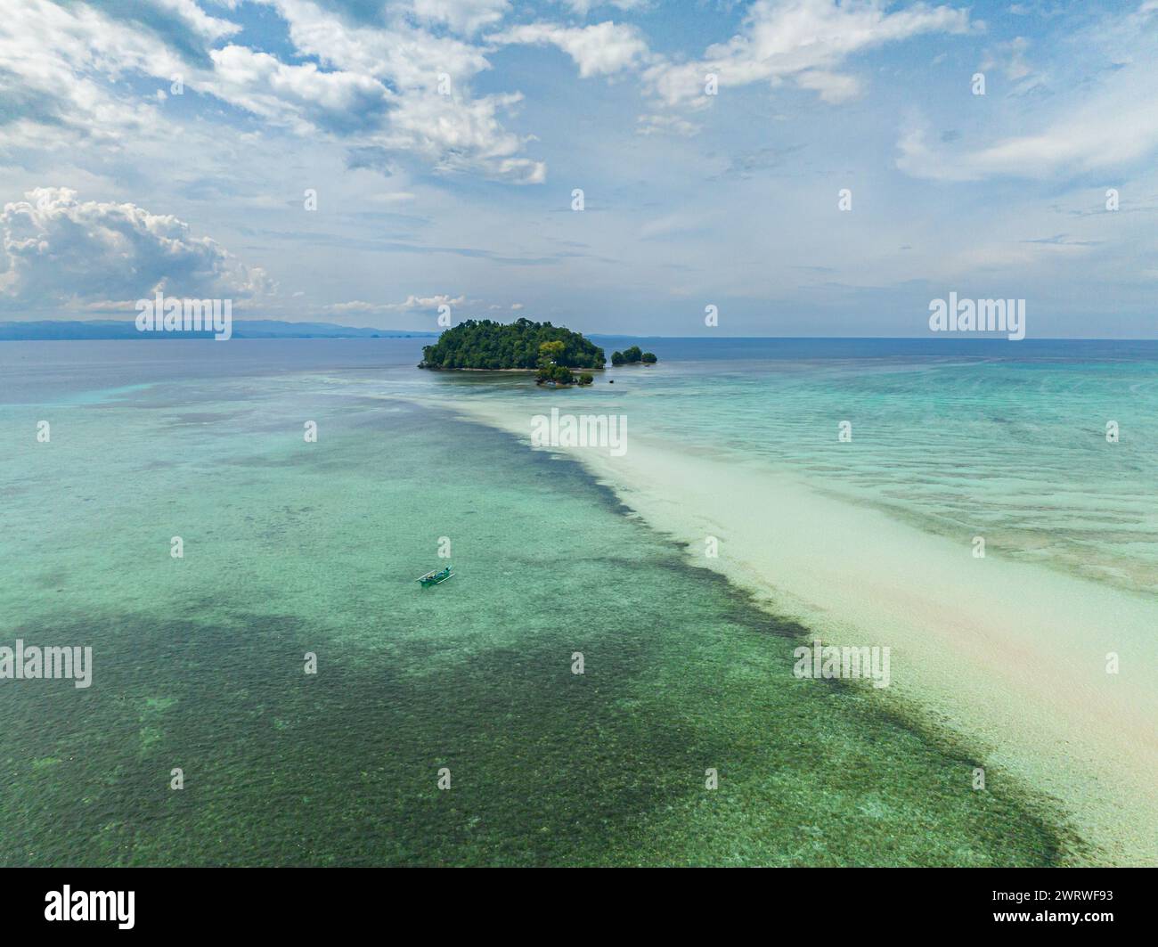 Tropical Islets surrounded by transparent azure water. Boats floating at white shoreline. Barobo, Surigao del Sur. Philippines. Stock Photo