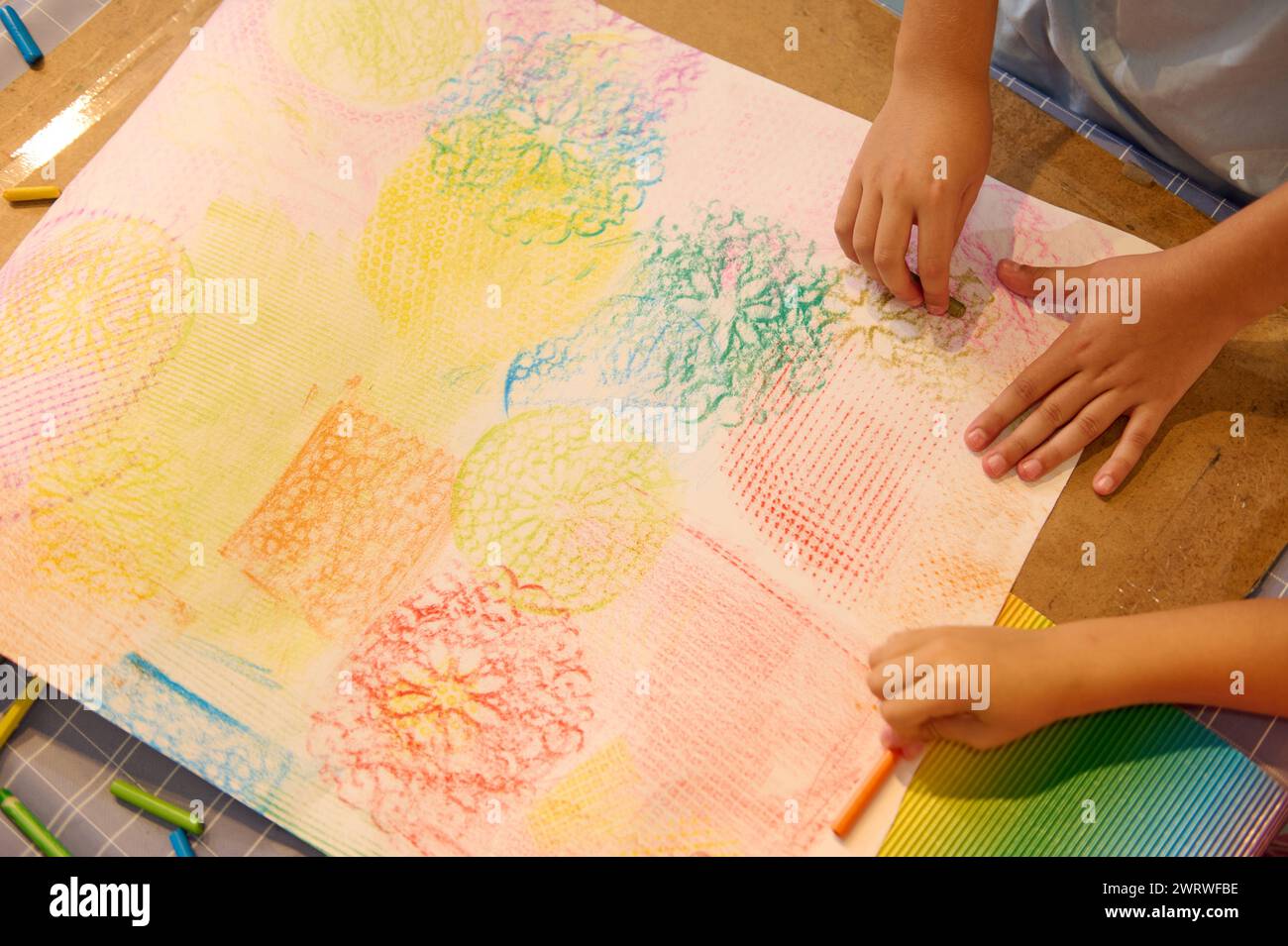 Top view close-up kids drawing with pastel color pencils on cardboard ...