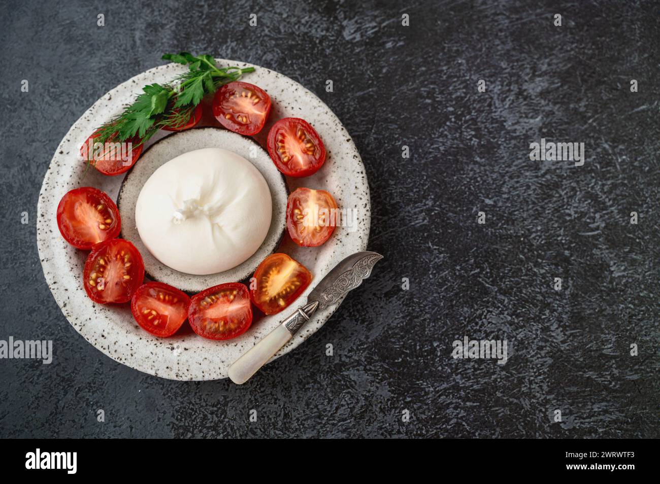 burrata with tomatoes. Caprese salad with tomatoes, burrata cheese and herbs. Soft cheese in a burrata bag. Copy space, Top view, flat lay. Stock Photo