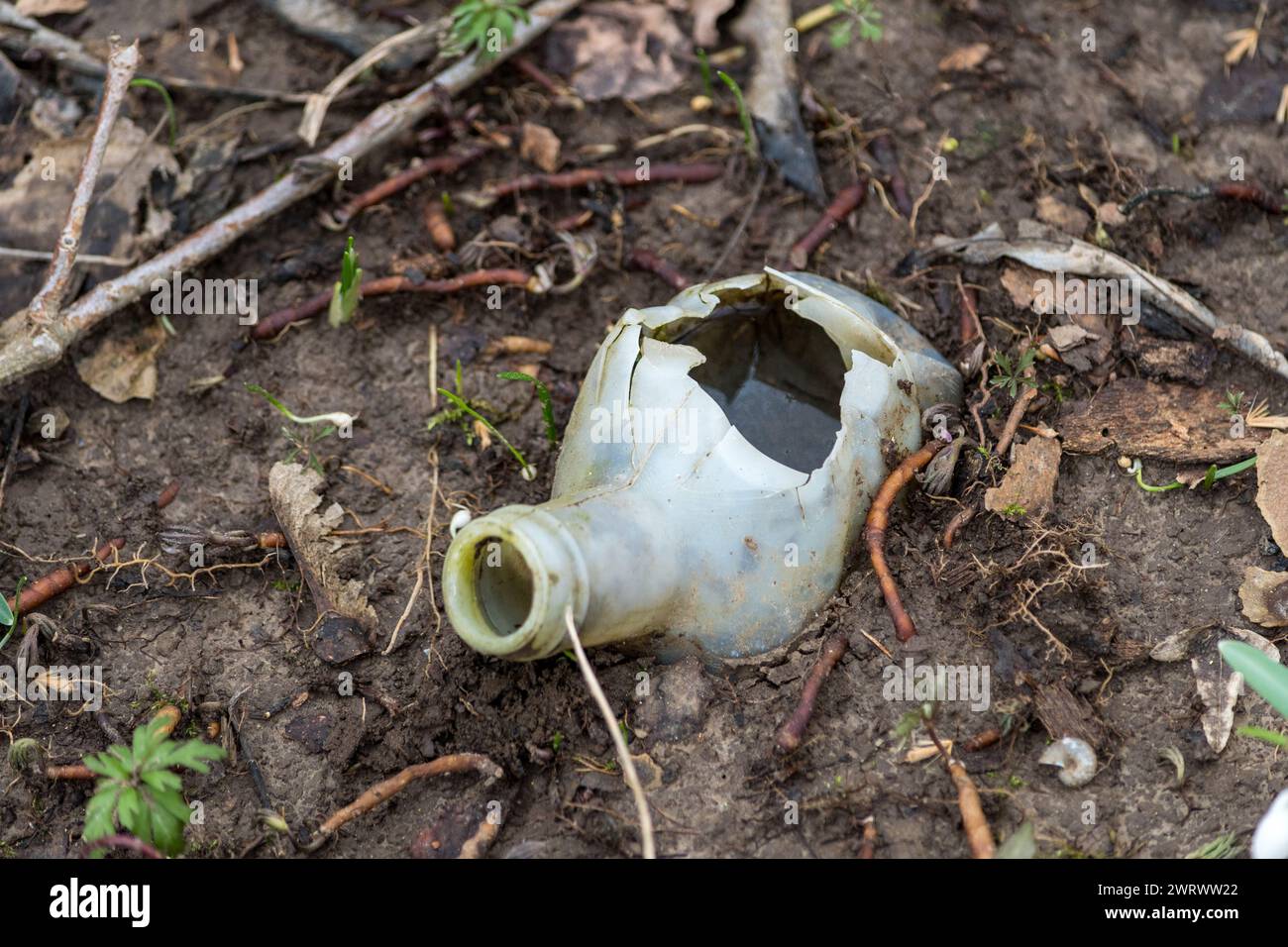 Top view of a portion of a plastic bottle hidden underground and abandoned in a forest. Polluting waste that is ruining our planet. Plastic materials Stock Photo