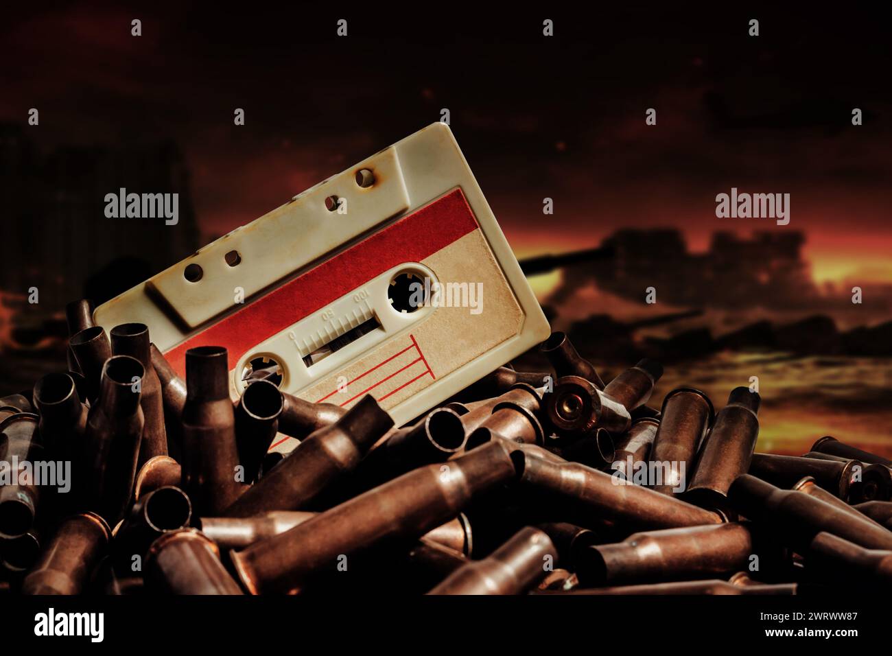 Photo of an old audio tape cassette on pile of bullets. Ruined city battlefield or wasteland background. Stock Photo