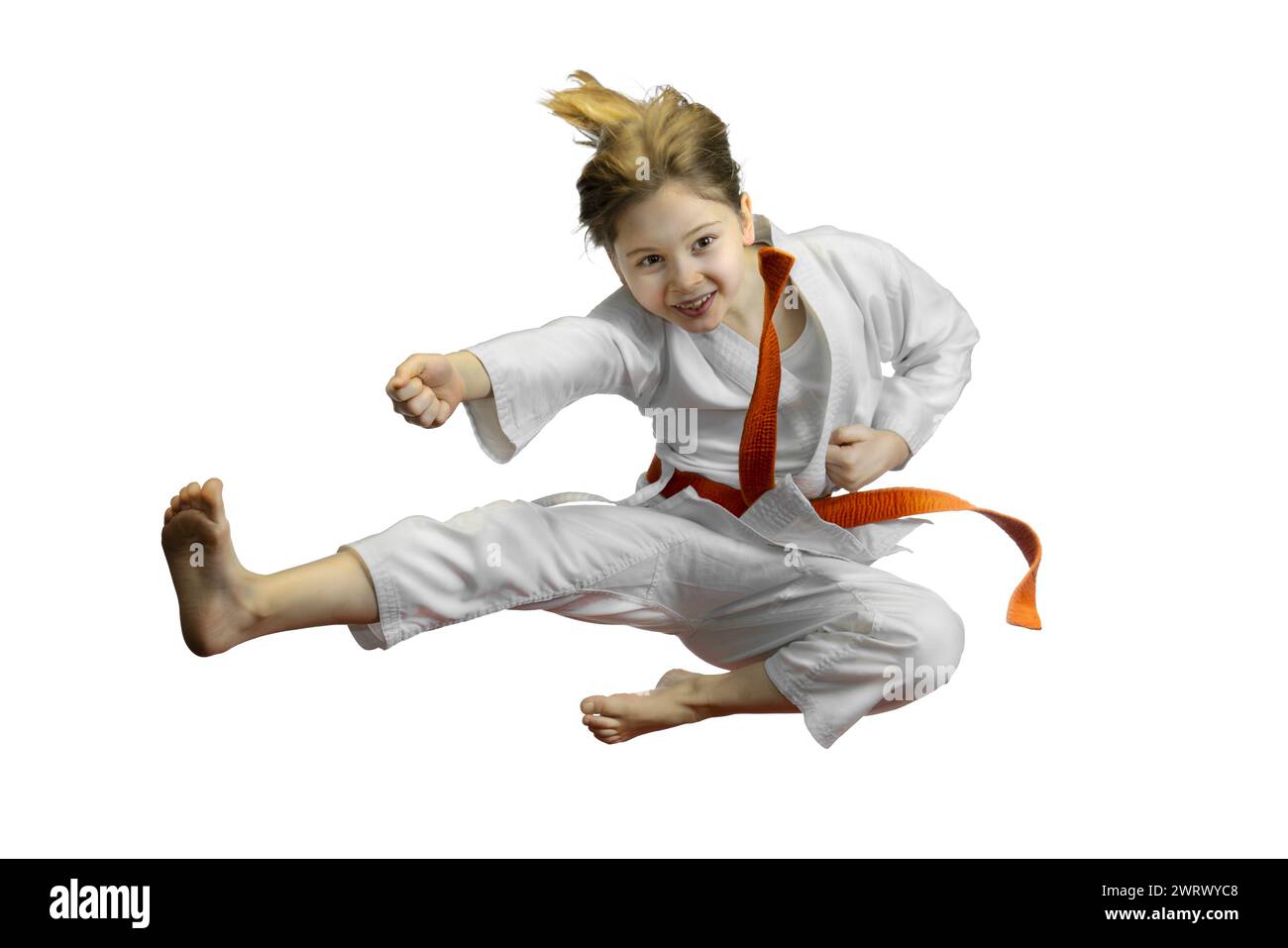 Energetic young girl performing a karate kick, isolated on white background Stock Photo