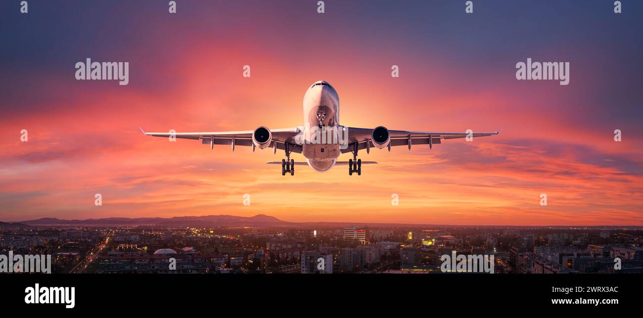 Airplane is flying in colorful sky over the city at night Stock Photo ...