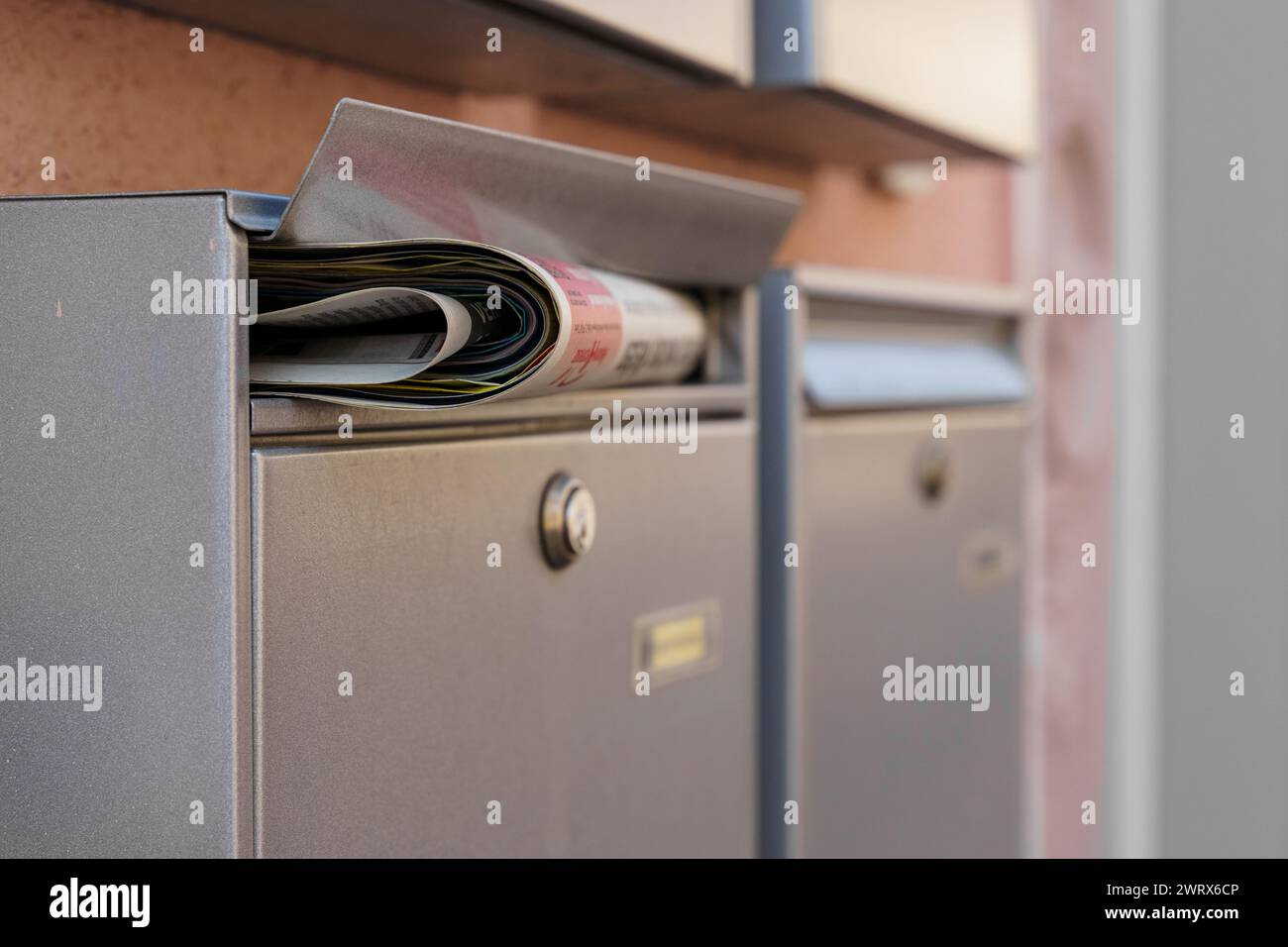 A mailbox filled with newspapers spilling out, indicating neglect or a lack of retrieval. Stock Photo