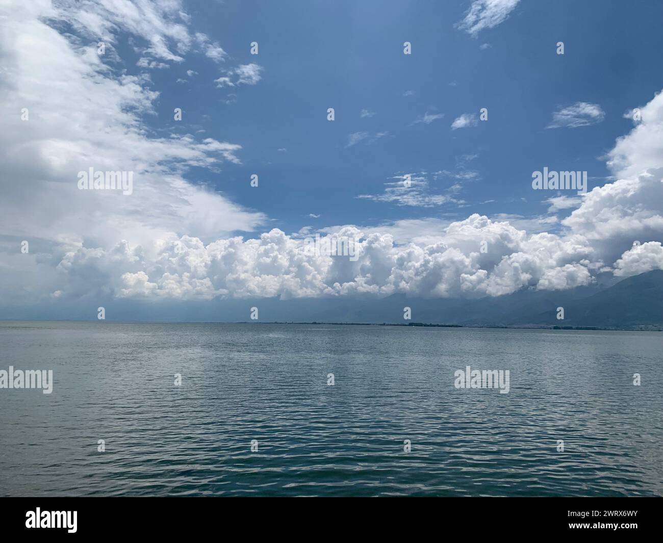 The calm waters of a lake with the horizon in the background under the blue sky Stock Photo