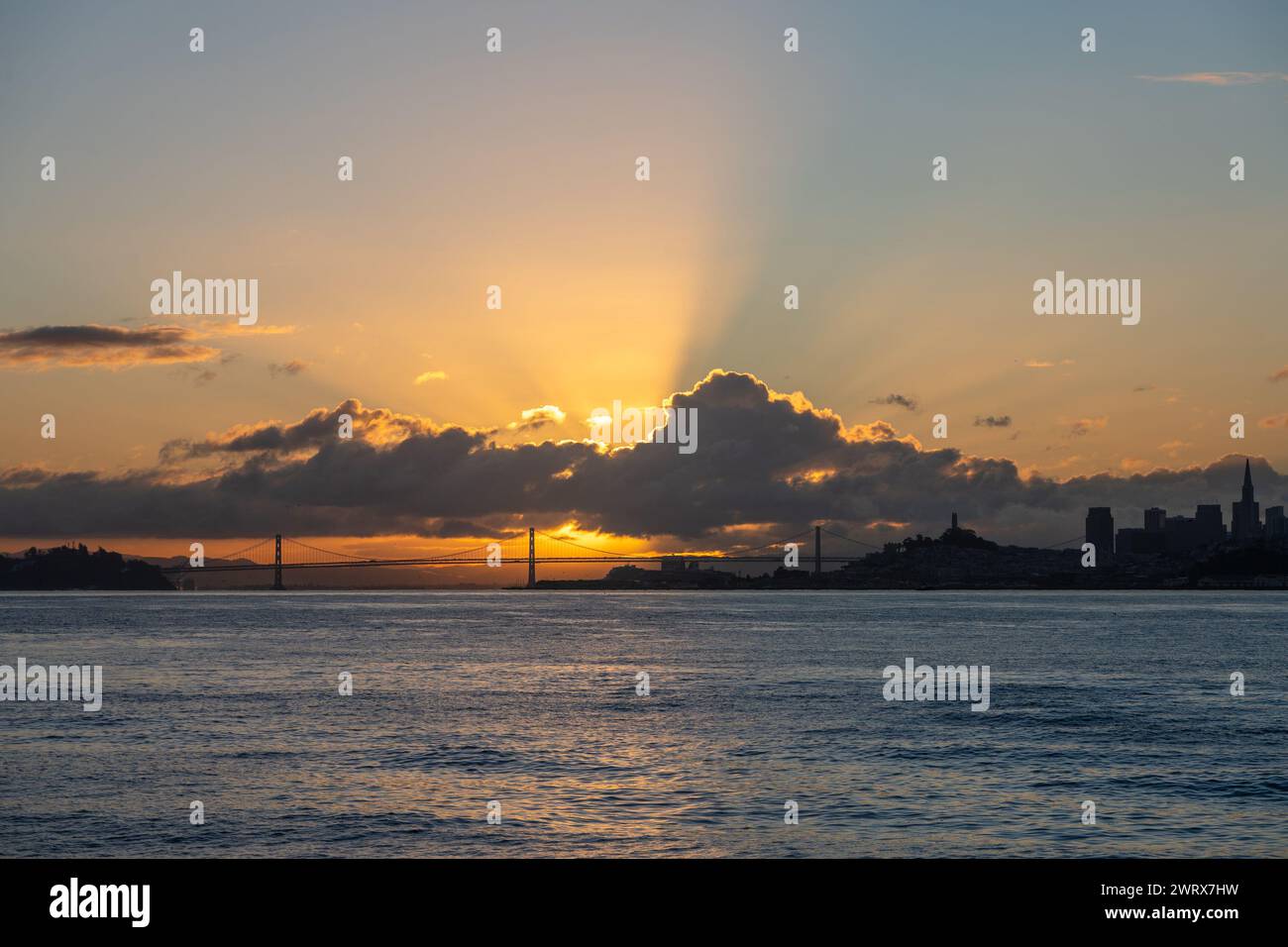 The sun is setting over the water, casting a warm glow over the city ...