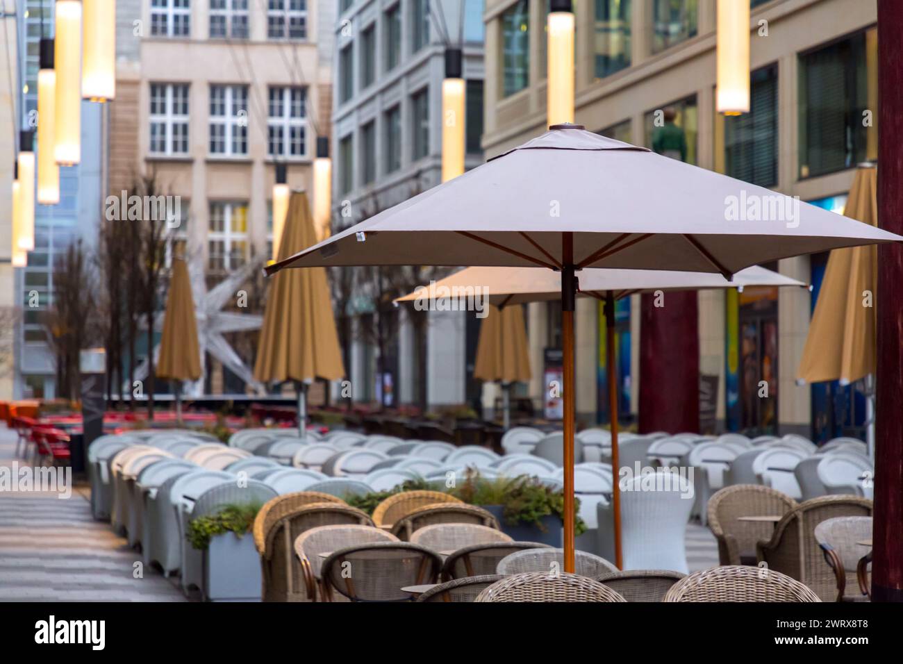 Tables and seats with parasols inside a mall, city life concept with no persons Stock Photo