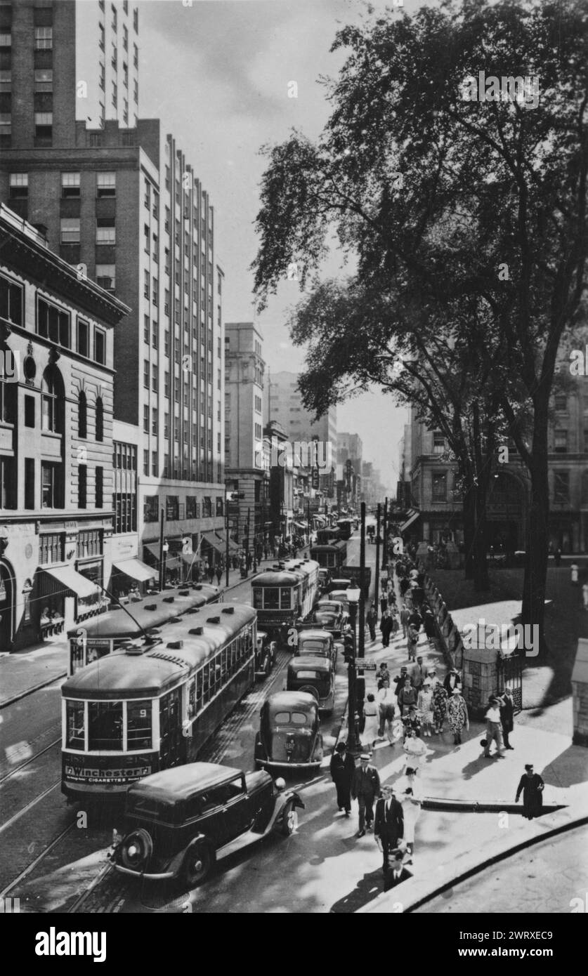 View of Sainte-Catherine Street looking west from the Morgan store, Montreal, QC, Canada  circa 1945.  Traffic of tramway, streetcars, and cars as well as large amount of pedestrians.   Vintage Street Photography photo by Wm. Notman & Son Stock Photo