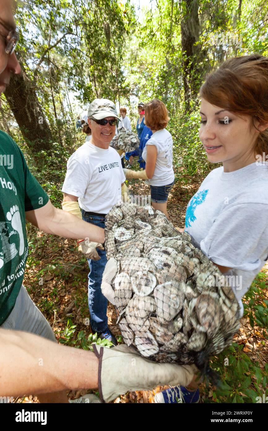 Volunteers use a bucket brigade to move bags of recycled oyster shells ...