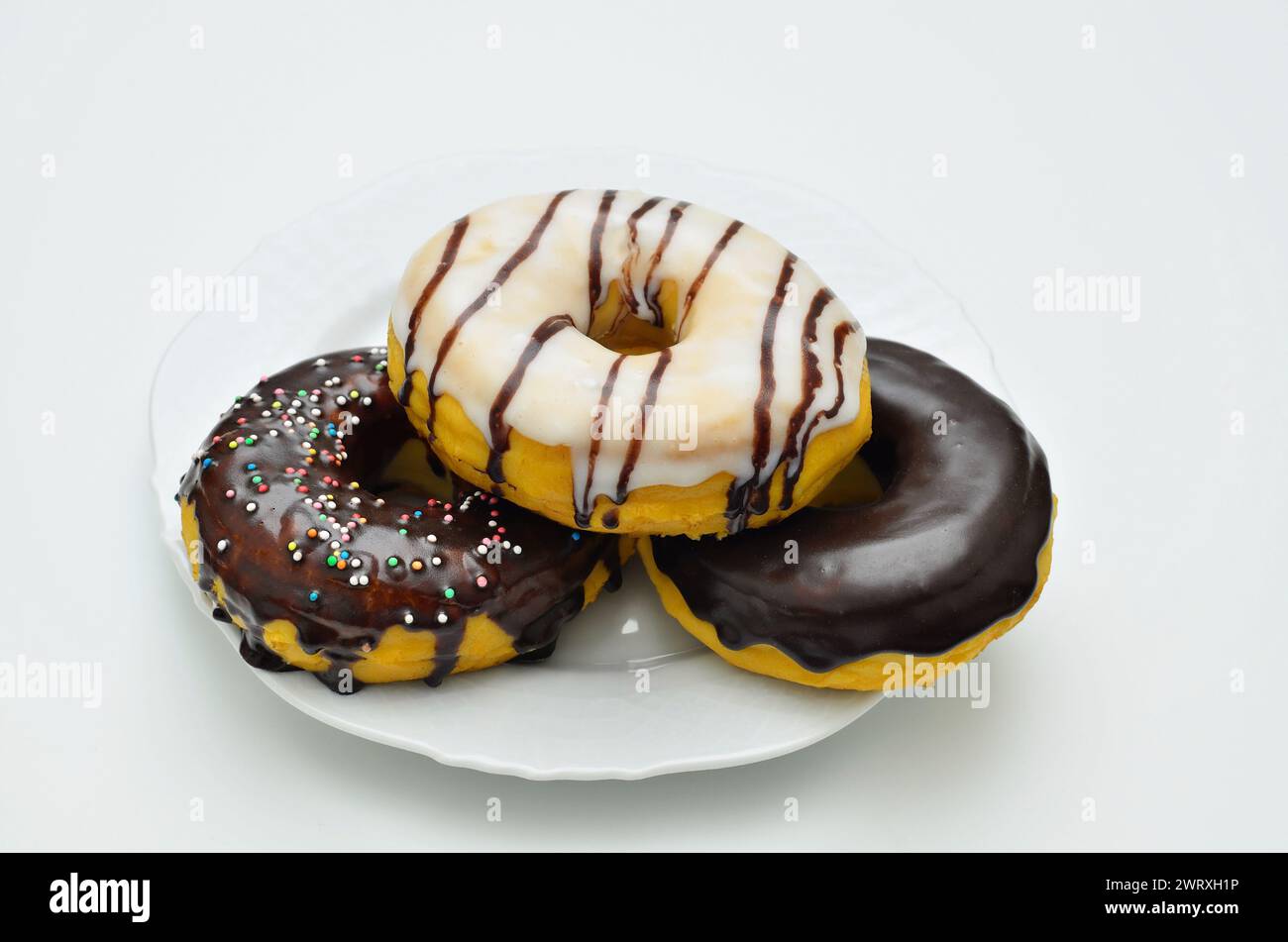 three assorted donuts on white plate, close up, isolated on white background Stock Photo