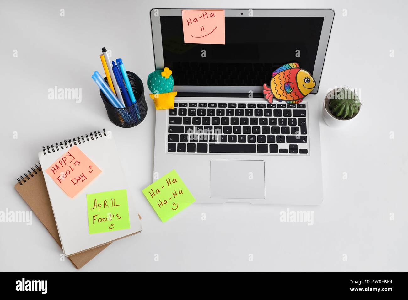 Workspace with laptop, funny sticky notes and paper fish on white