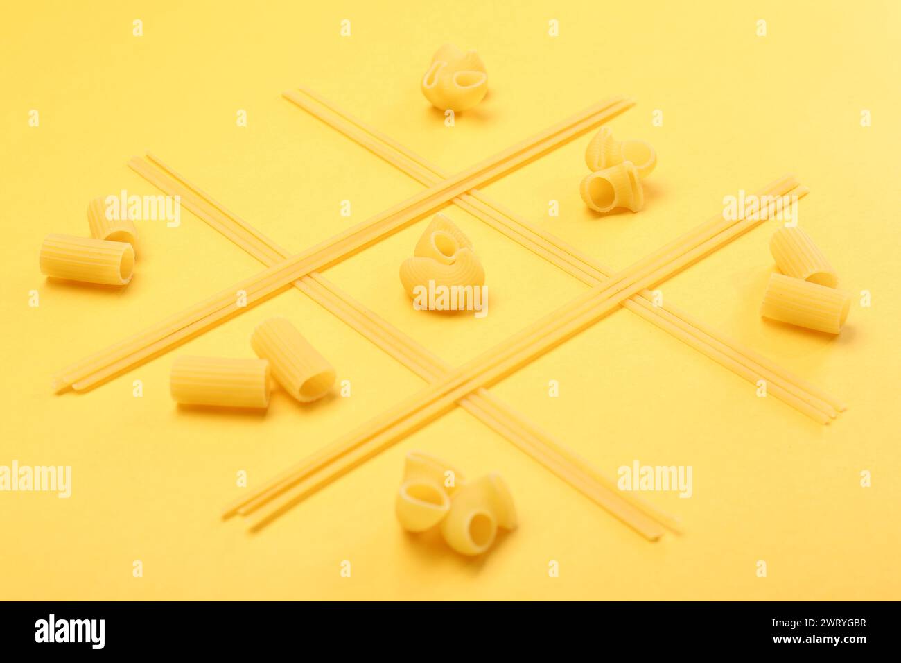 Tic tac toe game made with different types of pasta on yellow background Stock Photo