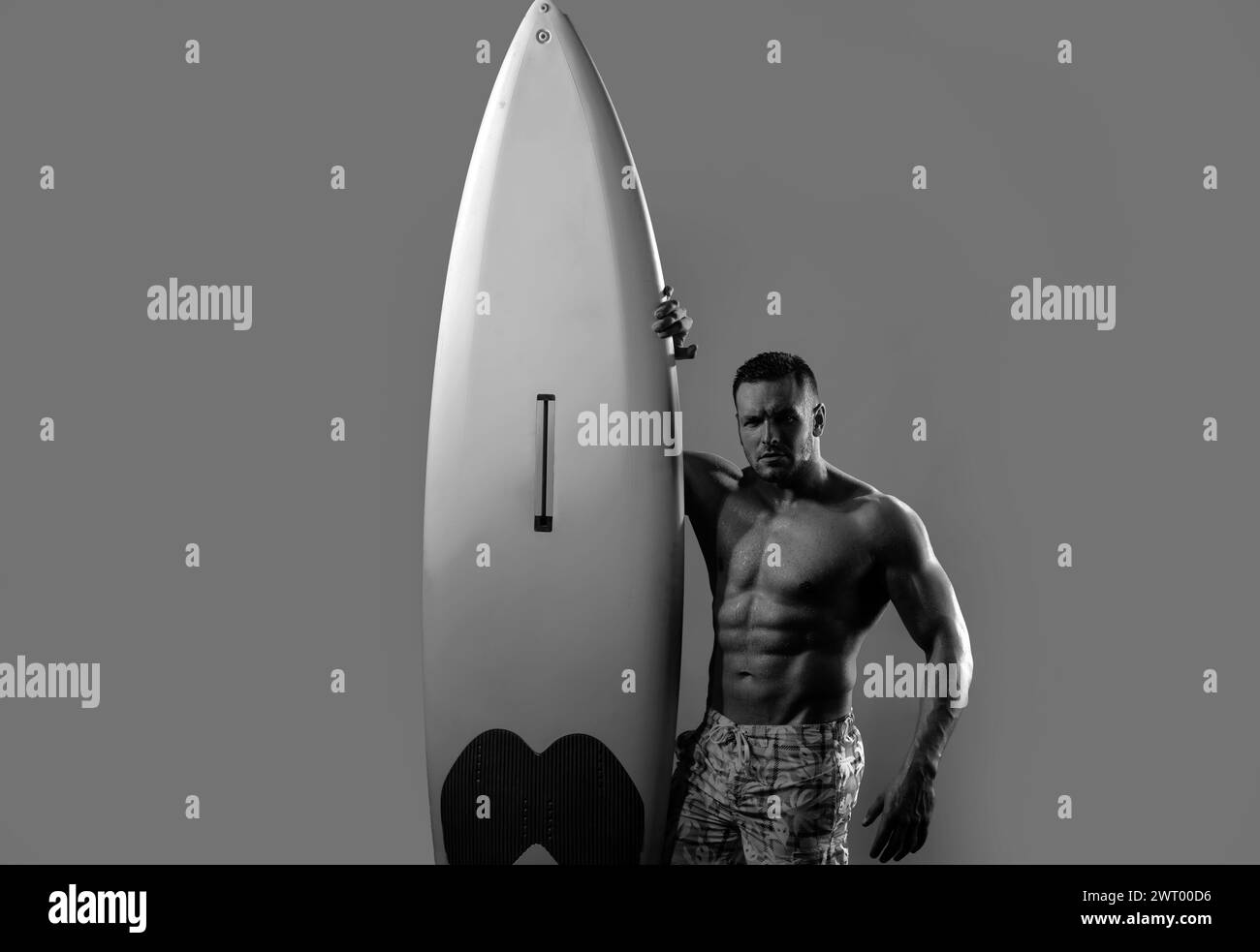 Handsome serfer man with serf board. Male fit with athletic body. Surfboard man with serf board. Surfer with a surfboard isolated on blue. Stock Photo