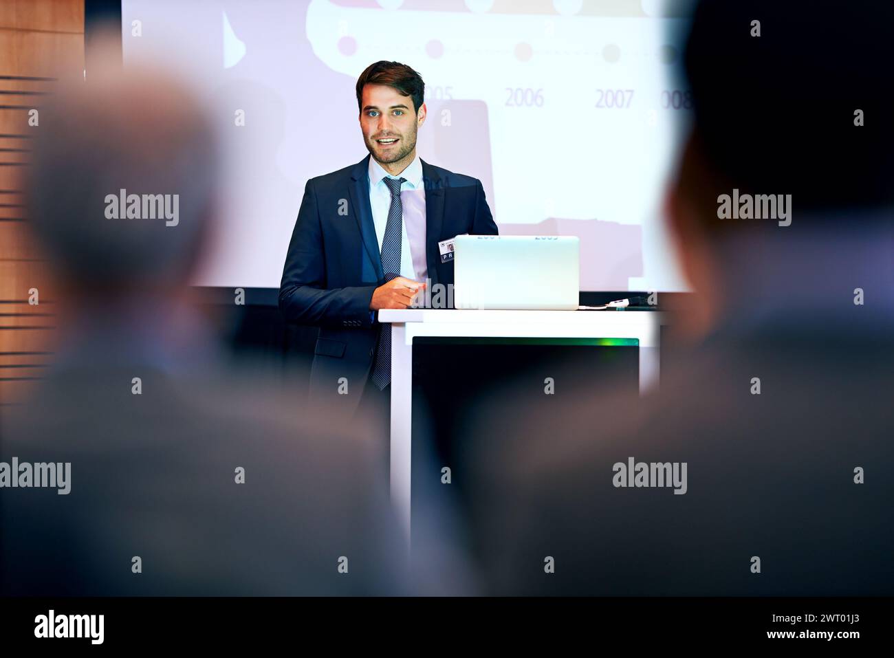 Business man, podium and presentation with projector screen, conference or workshop with laptop for slideshow. Corporate training, seminar and speaker Stock Photo