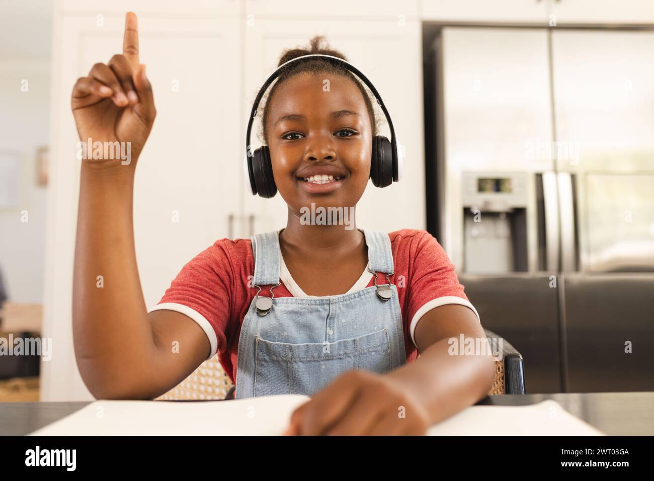 A young African American girl raises her hand during a lesson on a video call online school lesson Stock Photo