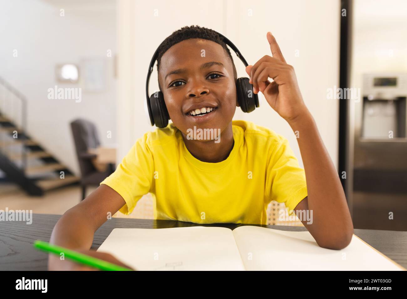 A young African American boy is studying with headphones on during an ...