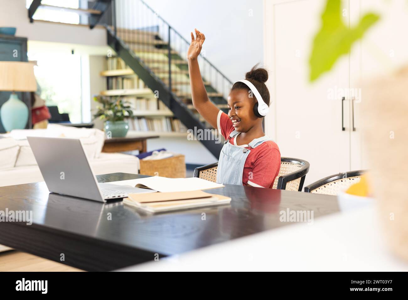 A young African American girl is engaged in an online school session at home Stock Photo
