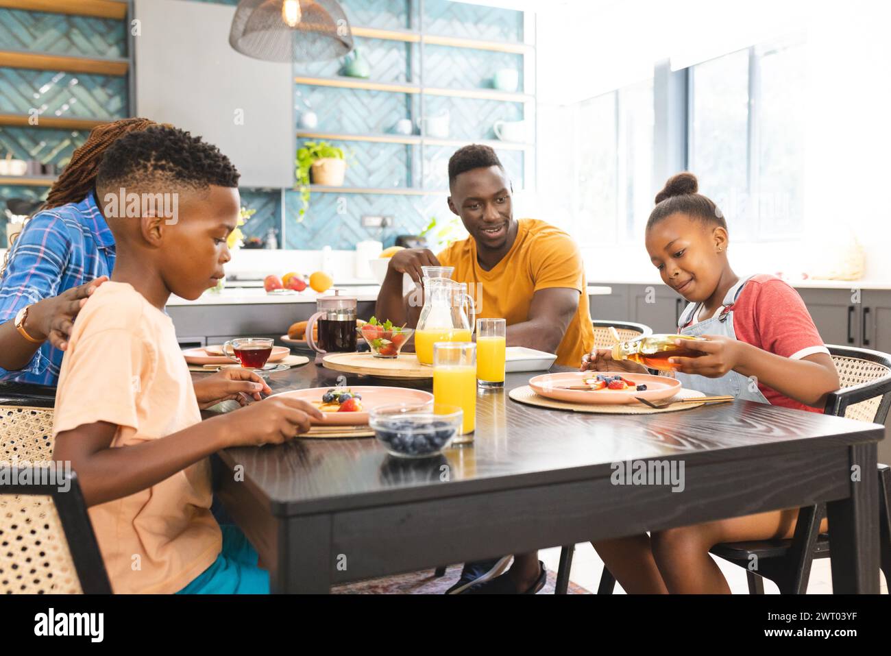 An African American family enjoys a breakfast together at home, diverse group Stock Photo