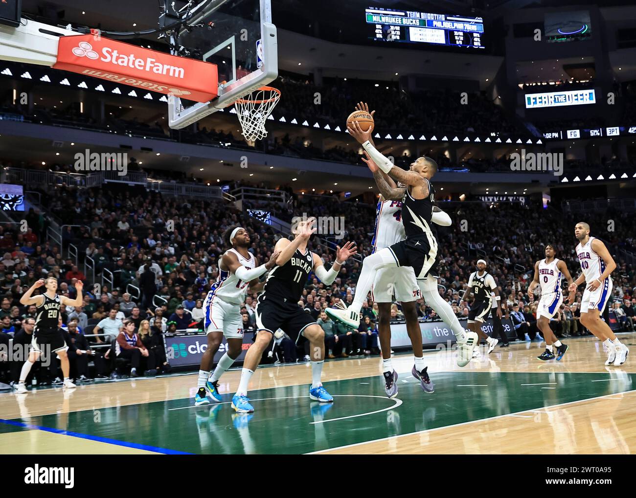 Milwaukee, USA. 14th Mar, 2024. Milwaukee Bucks guard Damian Lillard (top R) drives to the basket against Philadelphia 76ers forward Paul Reed (top L) during the NBA regular season game between Philadelphia 76ers and Milwaukee Bucks in Milwaukee, the United States, March 14, 2024. Credit: Joel Lerner/Xinhua/Alamy Live News Stock Photo