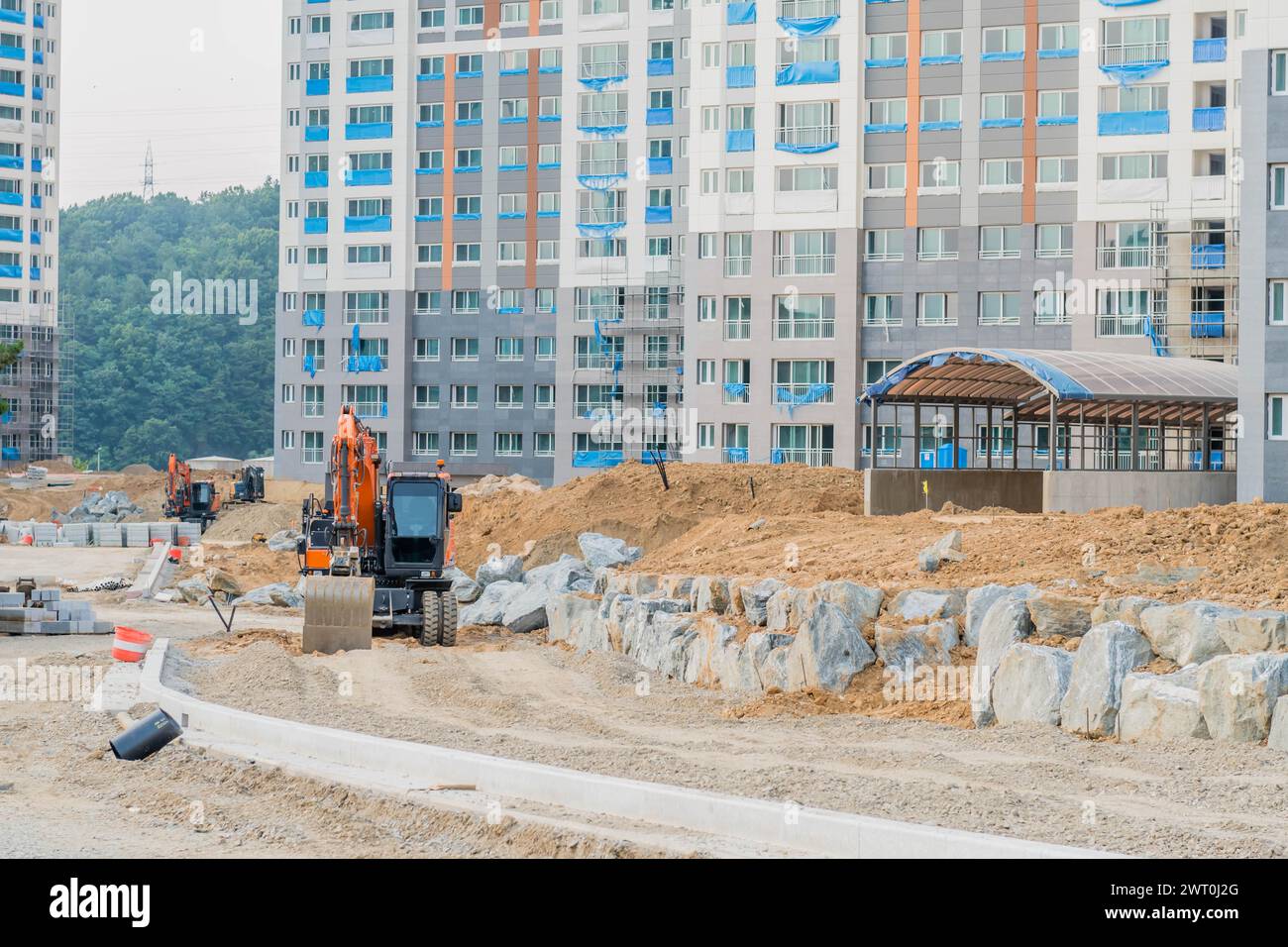 Backhoe parked on dirt road in front of unfinished high rise apartment in Daejeon South Korea Stock Photo