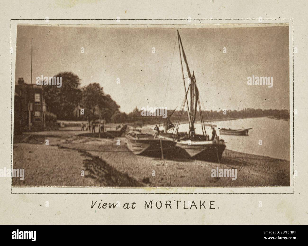 View at Mortlake. Henry W. Taunt, photographer (British, 1842 - 1922) about 1886 One of three tipped-in photographs illustrating a printed map of Richmond along the River Thames. The photograph shows a view of two boats on the bank of the river at Mortlake with others floating in the water. Several people can be seen scattered in the background and in the boats. (Recto, mount) lower center, below image, printed in black ink: 'View at [italicized] MORTLAKE.' Stock Photo