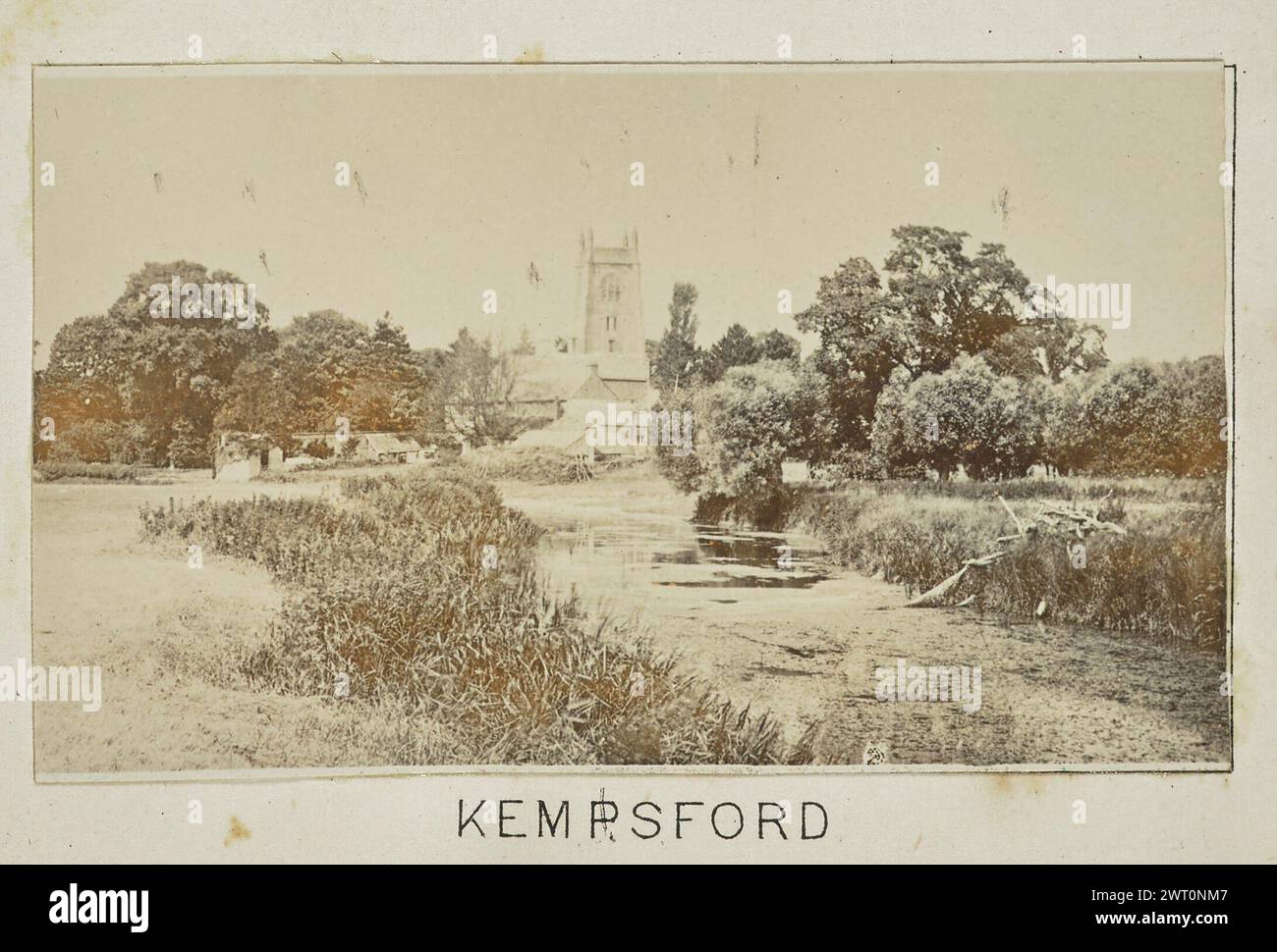 Kempsford. Henry W. Taunt, photographer (British, 1842 - 1922) 1897 One of three tipped-in photographs illustrating a printed map of Castle Eaton, Kempsford, and the surrounding area along the River Thames. The photograph shows a view of the river at Kempsford with St. Mary's Church and the surrounding buildings visible across a field in the distance. (Recto, mount) lower center, below image, printed in black ink: 'KEMPSFORD' Stock Photo