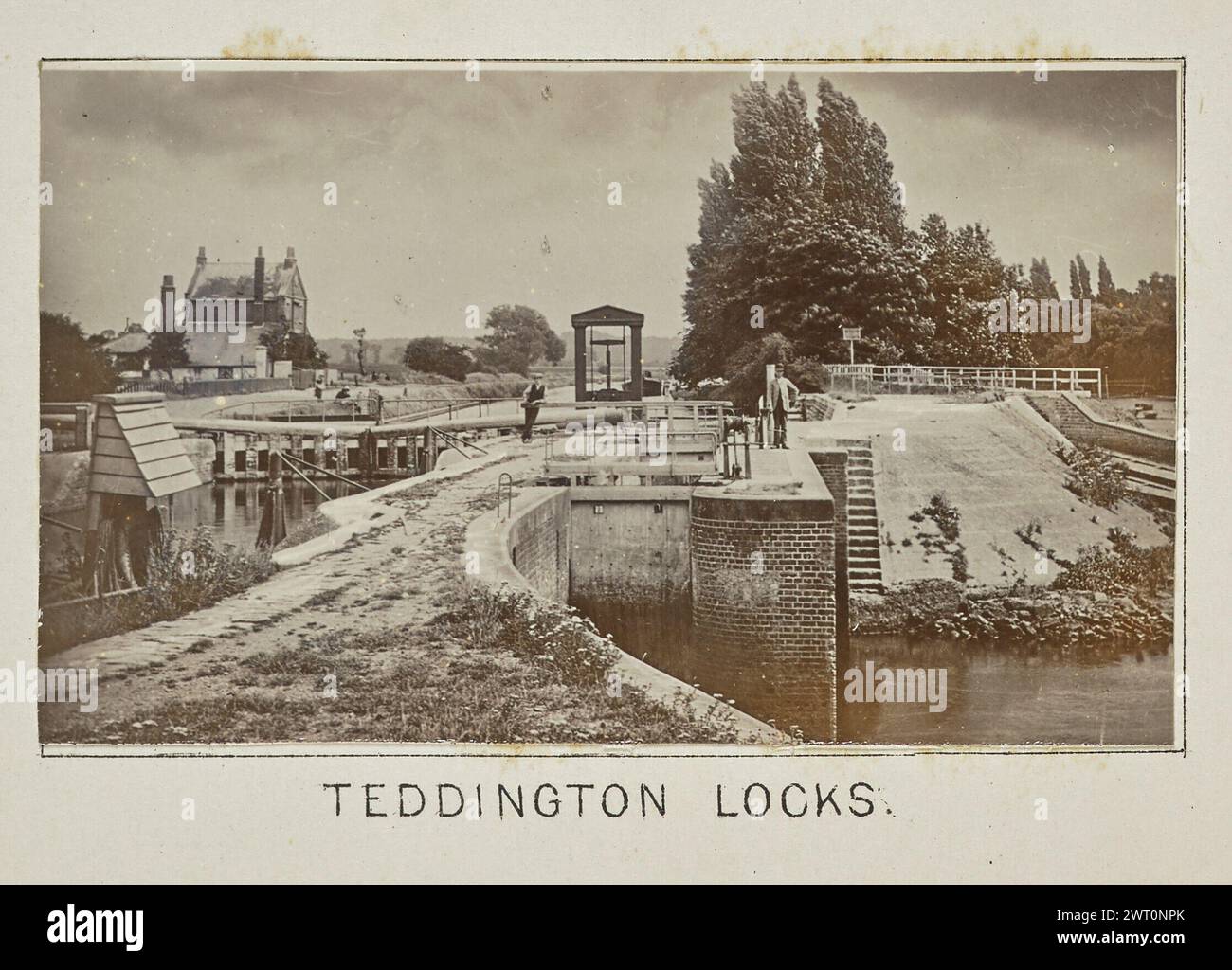 Teddington Locks. Henry W. Taunt, photographer (British, 1842 - 1922) 1897 One of three tipped-in photographs illustrating a printed map of Twickenham, Teddington, and the surrounding area along the River Thames. The photograph shows a view of the Teddington Lock on the river, with boats visible on the water in the background and a man standing on the lock leans against a railing. (Recto, mount) lower center, below image, printed in black ink: 'TEDDINGTON LOCKS.' Stock Photo